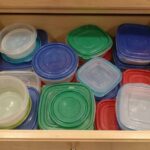 Organized Tupperware lids stored vertically inside a kitchen cabinet